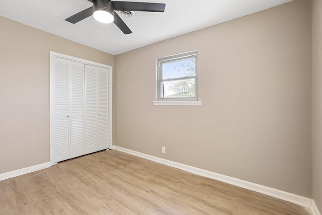 unfurnished bedroom with ceiling fan, a closet, and light hardwood / wood-style flooring