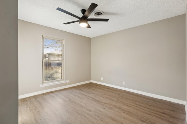 empty room with ceiling fan, a textured ceiling, and hardwood / wood-style floors