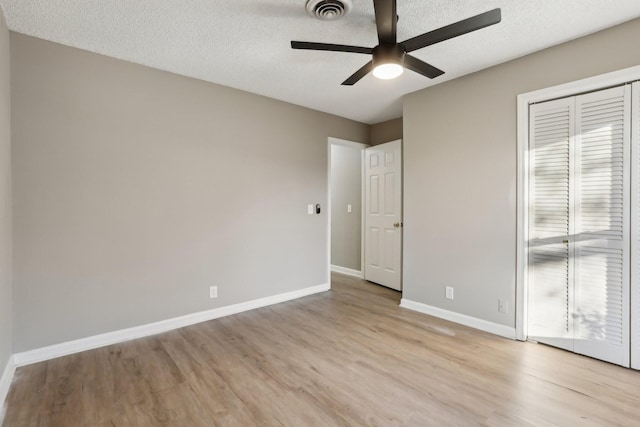 unfurnished bedroom with ceiling fan, light hardwood / wood-style floors, a textured ceiling, and a closet