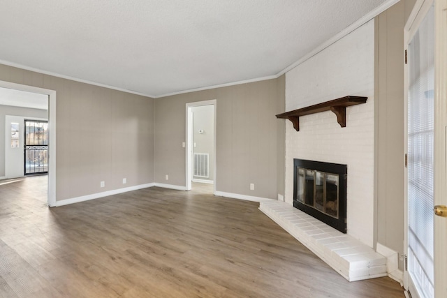 unfurnished living room with wood-type flooring, a fireplace, and crown molding