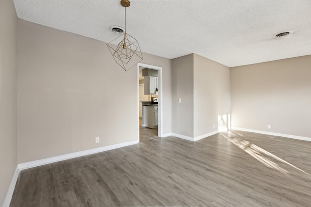 unfurnished room featuring dark wood-type flooring and a textured ceiling