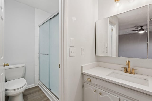 bathroom featuring hardwood / wood-style floors, vanity, toilet, walk in shower, and ceiling fan