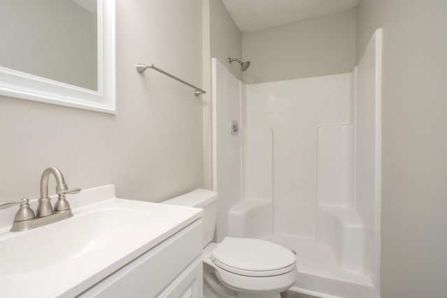 bathroom featuring toilet, a textured ceiling, a shower, and vanity