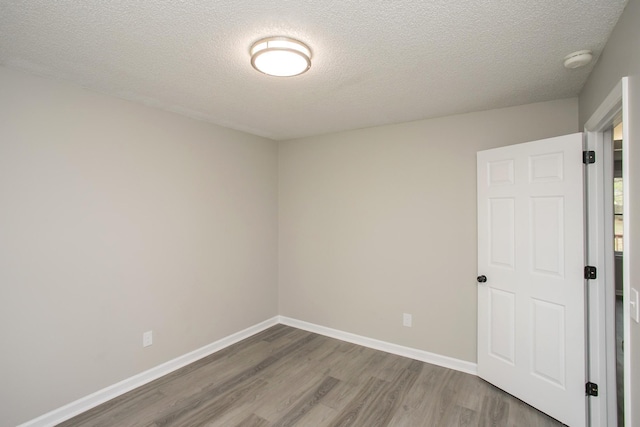 empty room with a textured ceiling and hardwood / wood-style floors