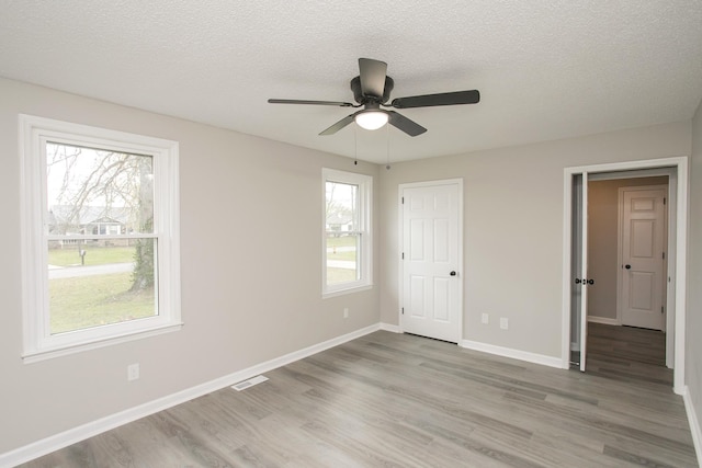 unfurnished bedroom with ceiling fan, light wood-type flooring, and a textured ceiling