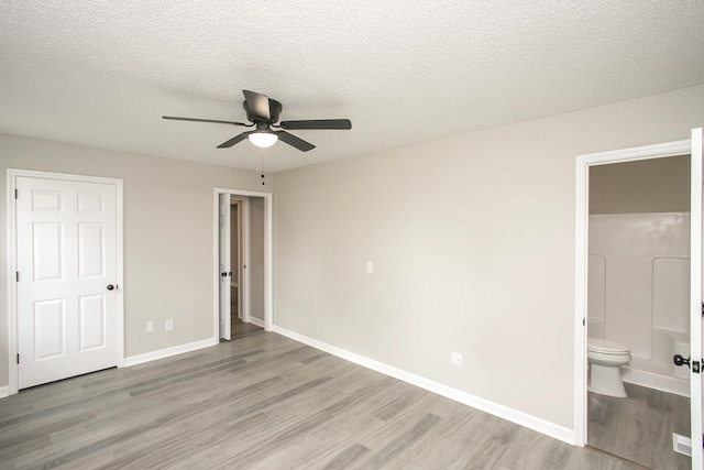 unfurnished bedroom featuring ensuite bathroom, a textured ceiling, ceiling fan, and light wood-type flooring