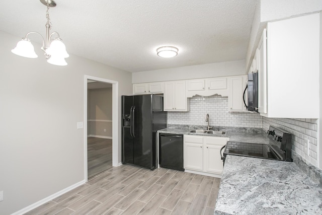 kitchen featuring hanging light fixtures, black appliances, backsplash, white cabinetry, and sink