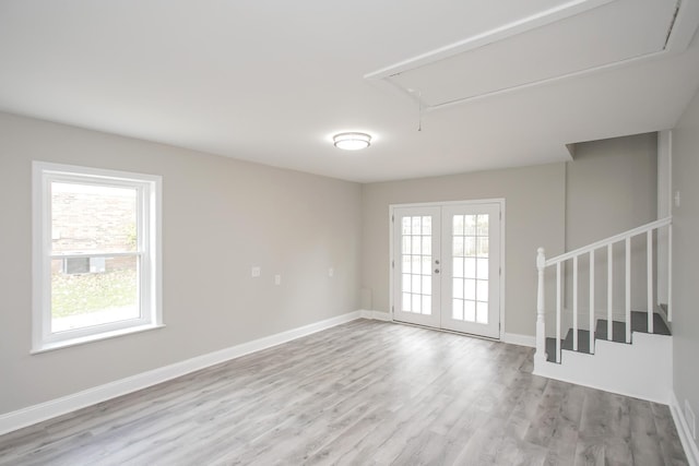 empty room featuring french doors, a wealth of natural light, and light hardwood / wood-style flooring