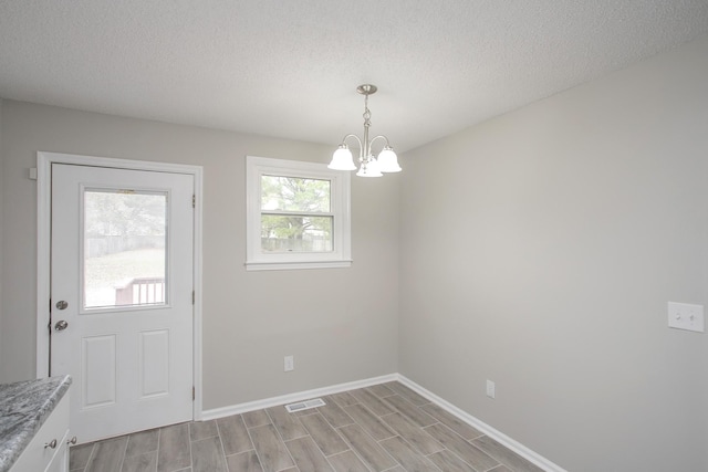 unfurnished dining area featuring an inviting chandelier and a textured ceiling