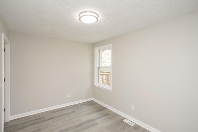 unfurnished room featuring a textured ceiling and light hardwood / wood-style flooring