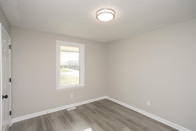 spare room with a textured ceiling and hardwood / wood-style floors