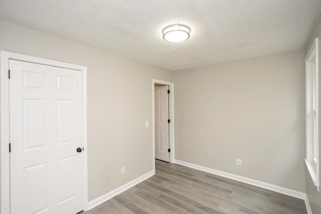 unfurnished bedroom featuring a textured ceiling, a closet, and hardwood / wood-style floors