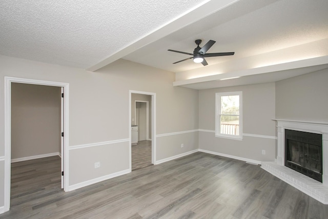 unfurnished living room with hardwood / wood-style floors, a brick fireplace, a textured ceiling, and ceiling fan