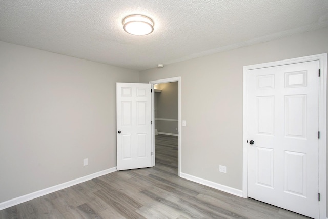 unfurnished bedroom featuring a textured ceiling, light wood-type flooring, and a closet