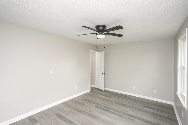 empty room with a textured ceiling, ceiling fan, and wood-type flooring