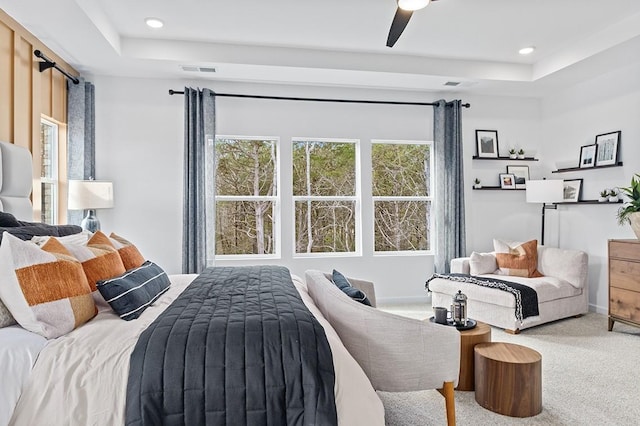 carpeted bedroom with ceiling fan and a tray ceiling