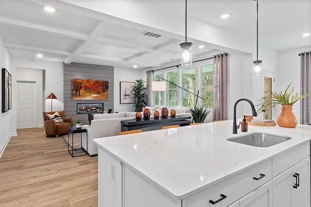 kitchen featuring sink, a fireplace, white cabinetry, and hanging light fixtures