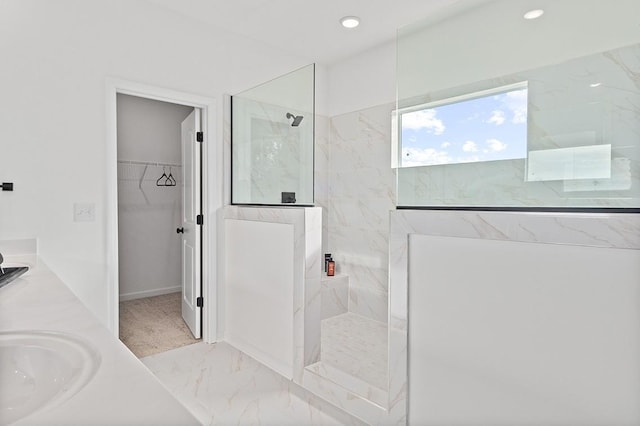 bathroom with a tile shower and vanity