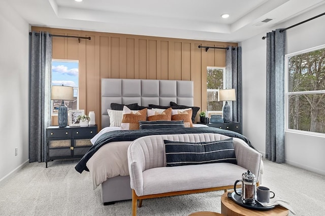 bedroom with a raised ceiling and light colored carpet