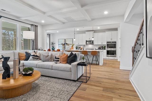 living room with coffered ceiling, light wood-type flooring, and beamed ceiling