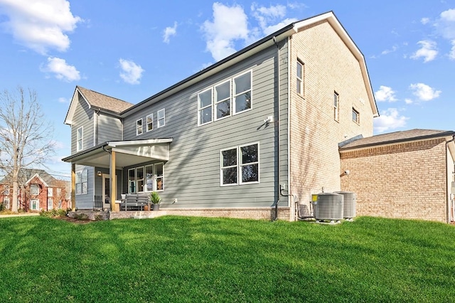 rear view of property featuring a yard, central AC, and a patio area