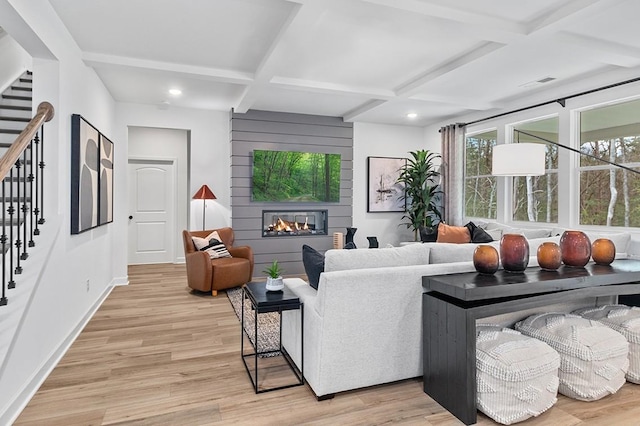 living room featuring a fireplace, light wood-type flooring, beam ceiling, and coffered ceiling