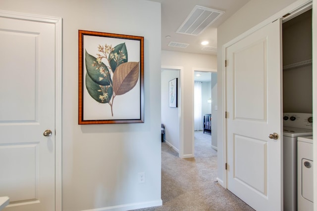 hallway featuring washer / clothes dryer and light carpet