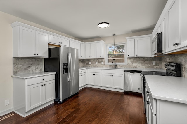 kitchen featuring stainless steel appliances, white cabinets, sink, and pendant lighting