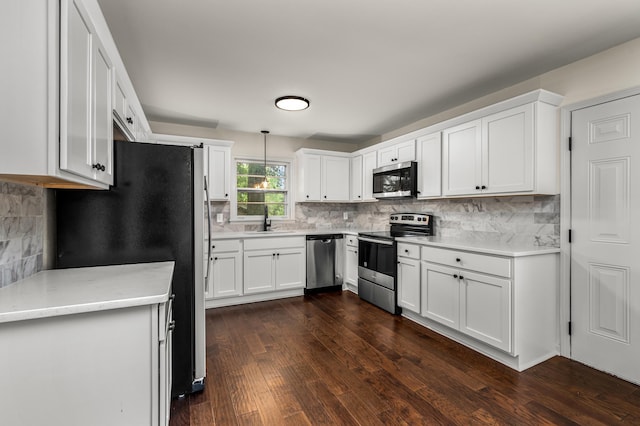 kitchen featuring appliances with stainless steel finishes, hanging light fixtures, white cabinetry, and sink