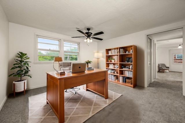 carpeted office space featuring ceiling fan