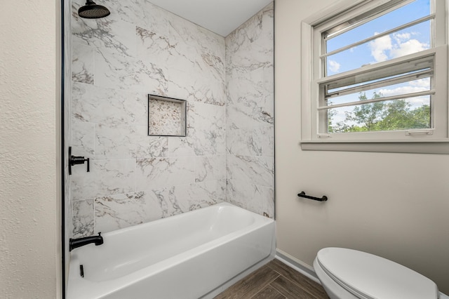 bathroom featuring toilet, a wealth of natural light, and tiled shower / bath