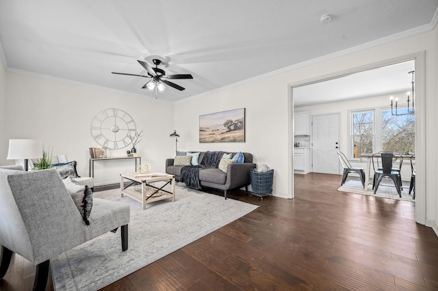 living room featuring dark wood-style floors, ornamental molding, and ceiling fan with notable chandelier