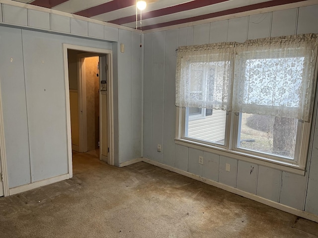 carpeted spare room with beam ceiling