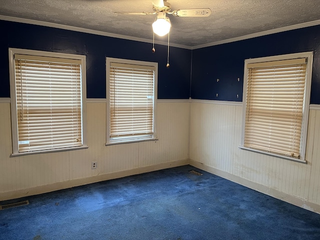 carpeted empty room featuring ceiling fan, crown molding, and a textured ceiling