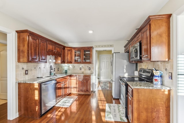 kitchen featuring stainless steel appliances, dark wood-type flooring, light stone countertops, and sink