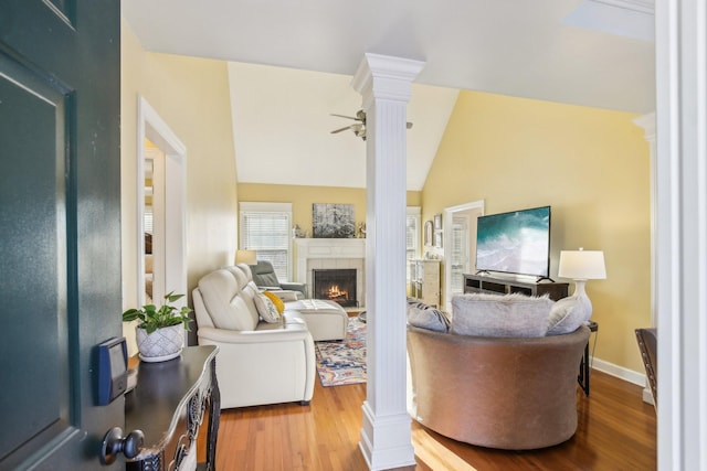 living room featuring hardwood / wood-style floors, lofted ceiling, decorative columns, a fireplace, and ceiling fan