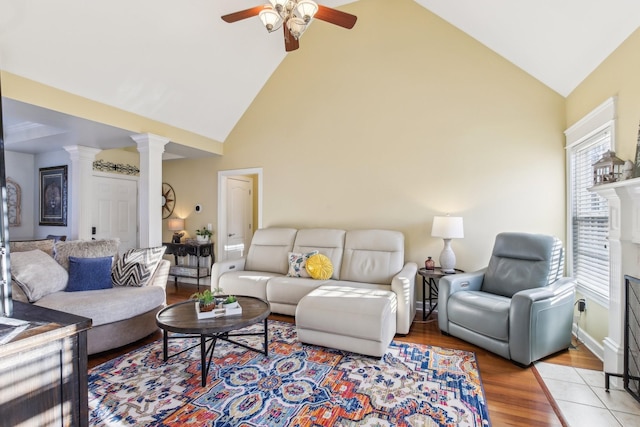 living room with ceiling fan, light hardwood / wood-style flooring, high vaulted ceiling, and ornate columns