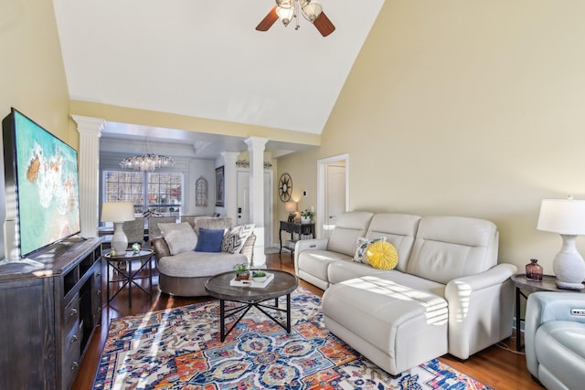 living room with ceiling fan with notable chandelier, wood-type flooring, high vaulted ceiling, and decorative columns