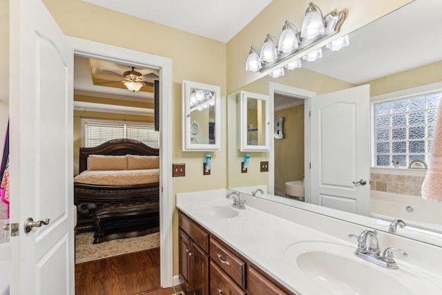 bathroom with hardwood / wood-style floors, toilet, vanity, ceiling fan, and a bathtub