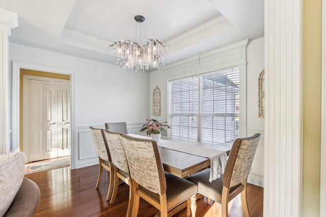 dining room with a notable chandelier, dark wood-type flooring, crown molding, and a tray ceiling