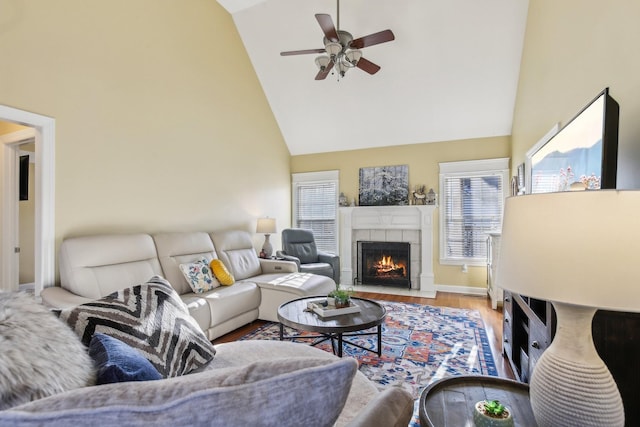 living room featuring ceiling fan, a tile fireplace, high vaulted ceiling, and hardwood / wood-style flooring