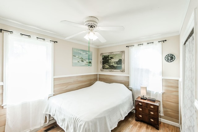 bedroom with ceiling fan, crown molding, and wood-type flooring