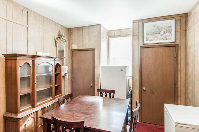 dining area featuring wooden walls and dark carpet