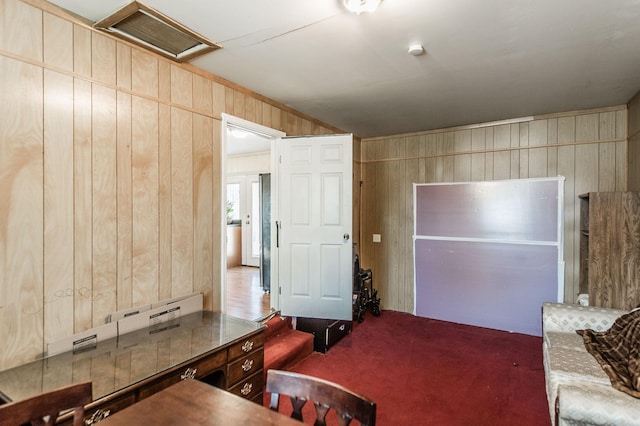 carpeted living room with wood walls