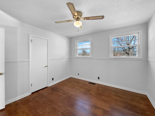 spare room featuring a textured ceiling, ceiling fan, and dark wood-type flooring