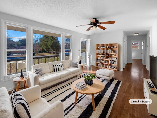 living room featuring ceiling fan, a wealth of natural light, dark hardwood / wood-style floors, and a textured ceiling