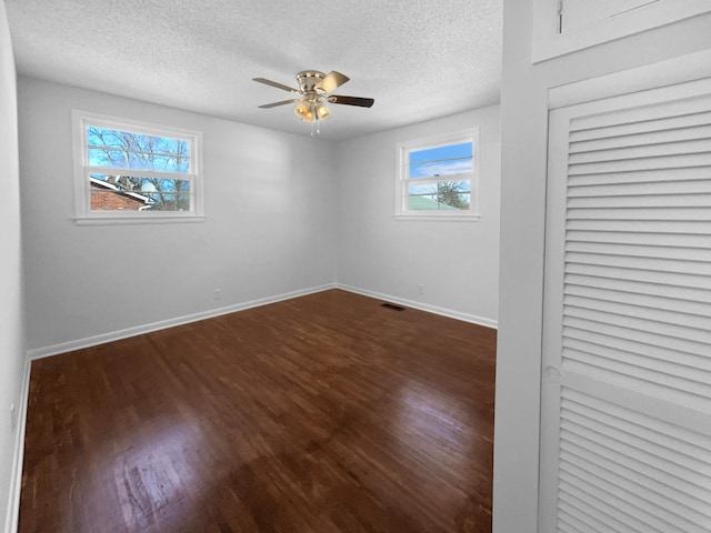 empty room featuring a textured ceiling, ceiling fan, and dark wood-type flooring