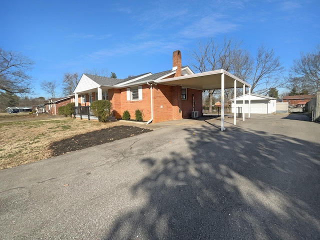 view of property exterior featuring a garage, a porch, a carport, and an outdoor structure