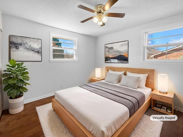 bedroom with ceiling fan, a textured ceiling, and dark hardwood / wood-style floors