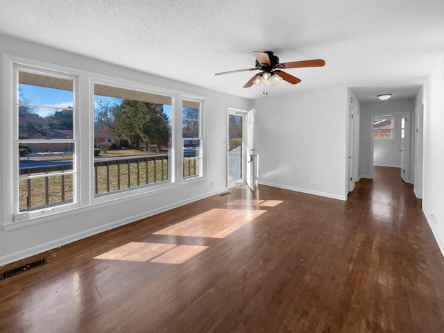 empty room featuring a textured ceiling, ceiling fan, and dark wood-type flooring